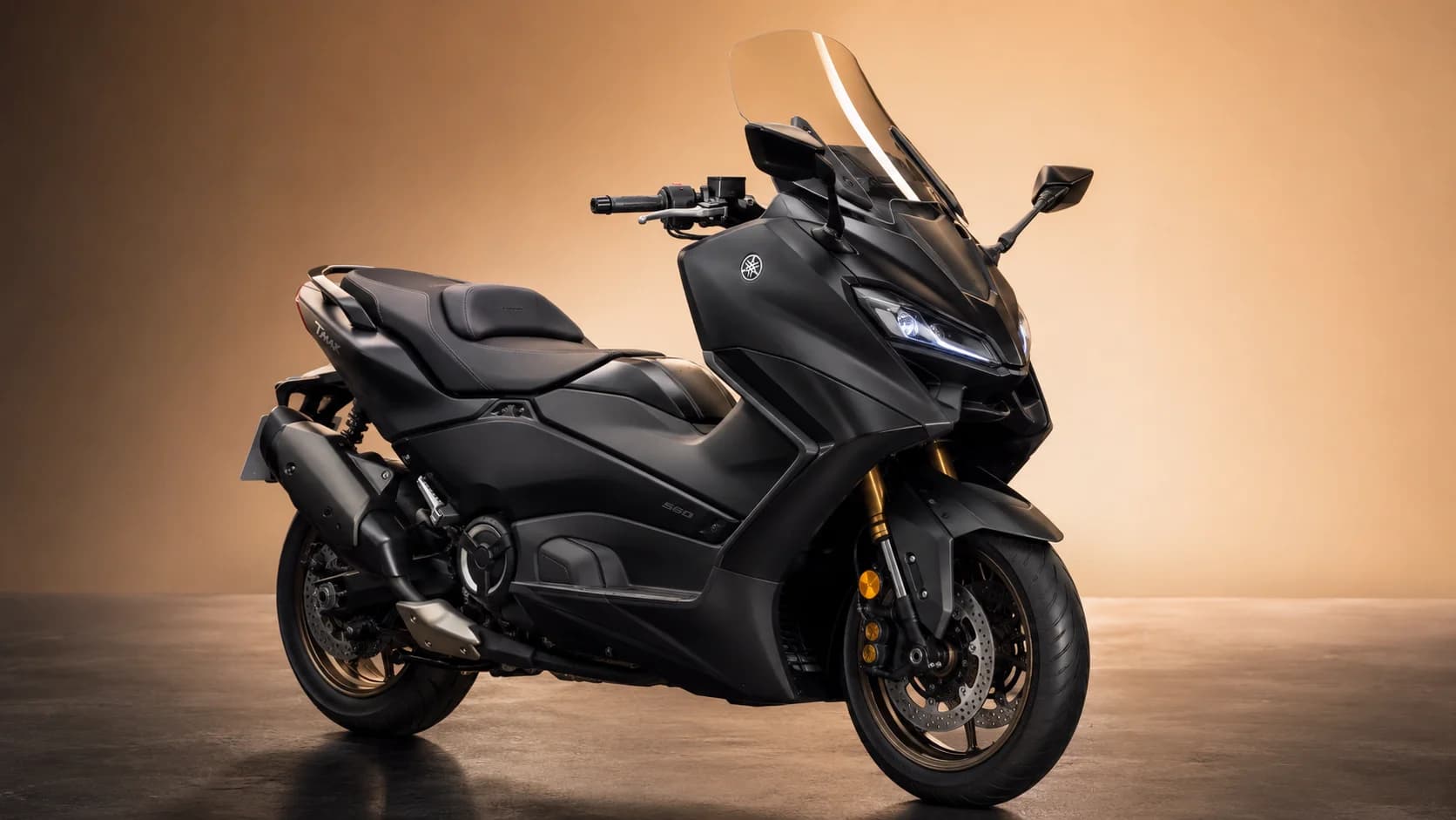 Yamaha TMAX 560 noir mat vu de trois quarts avant, sur fond ambré